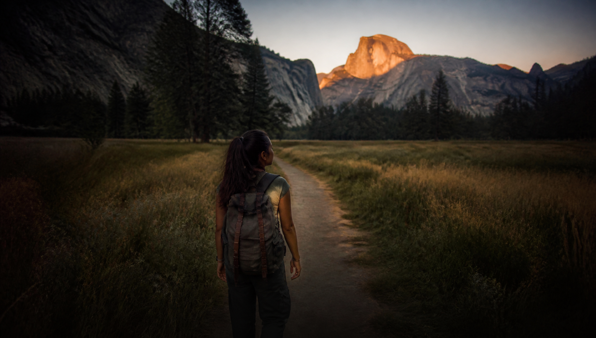 Woman walking toward Yosemite mountains at sunset